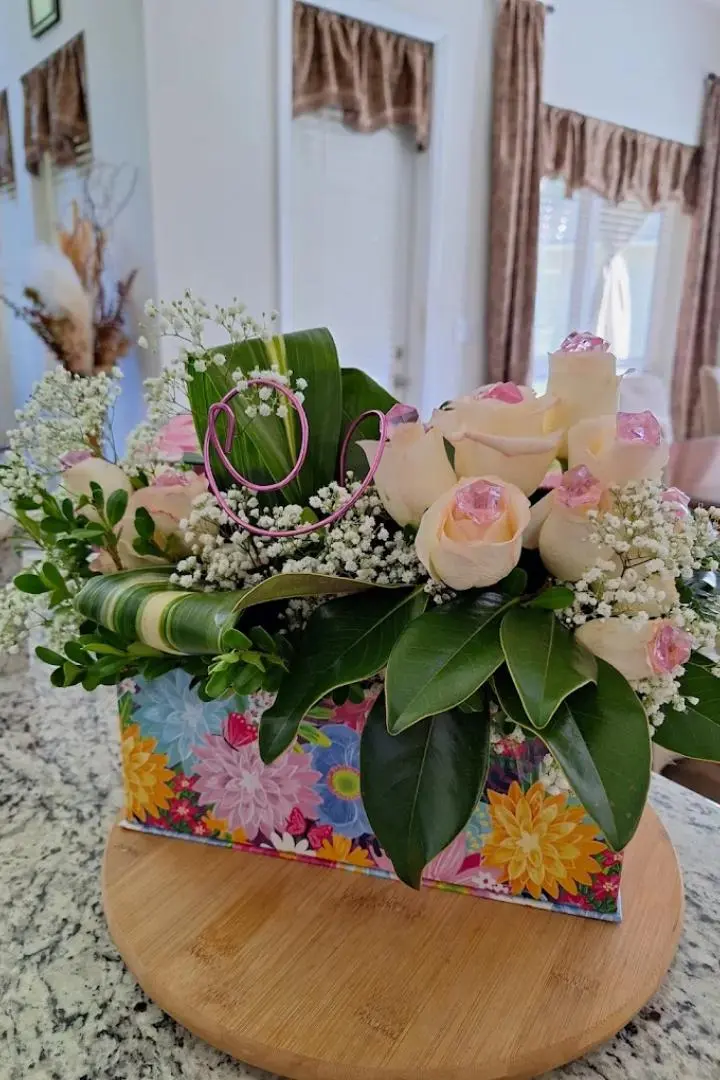 Mother's Day flower arrangement featuring white pink-ridged roses in a boxed arrangement with pink ribbon. Mother's Day flower arrangement featuring white pink-ridged roses in a boxed arrangement with pink ribbon.
