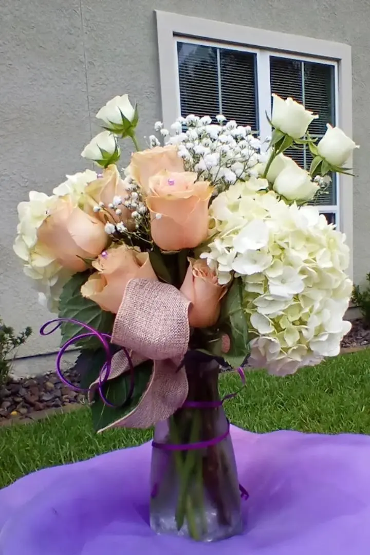 Mother's Day floral arrangement, featuring pink and white roses in glass vase with purple ribbon. Mother's Day floral arrangement, featuring pink and white roses in glass vase with purple ribbon.