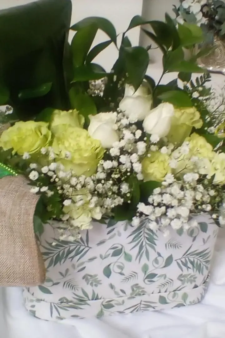Mother's Day floral arrangement featuring light-green and white roses in a green and white box container. Mother's Day floral arrangement featuring light-green and white roses in a green and white box container.