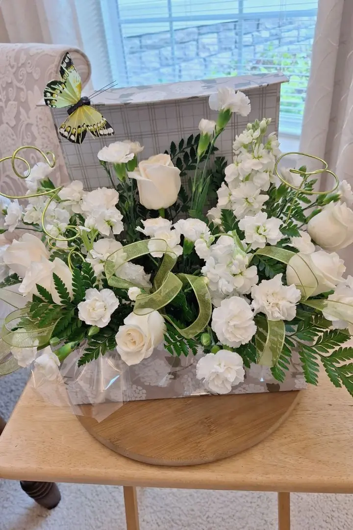 Mother's Day floral arrangement featuring 12 white roses with white flowers and butterfly decorations, designed by Lorraine for a customer in Orange Park, FL Mother's Day floral arrangement featuring 12 white roses with white flowers and butterfly decorations, designed by Lorraine for a customer in Orange Park, FL