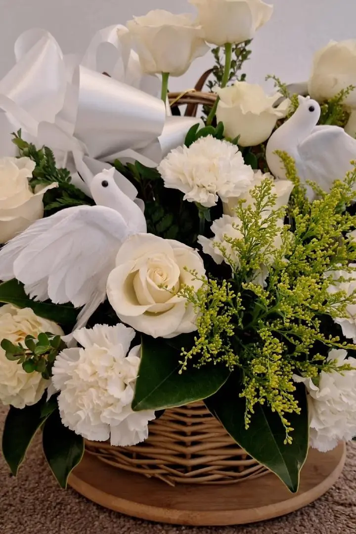 A sympathy floral arrangement with white roses and white carnations with dove decoration, designed by Lorraine for a funeral in Naval Air Station Jacksonville, FL.